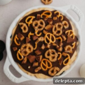 Decadent No-Bake Oreo Peanut Butter Pie 9 An overhead shot of a pie dish with a peanut butter pie covered in ganache and pretzels.