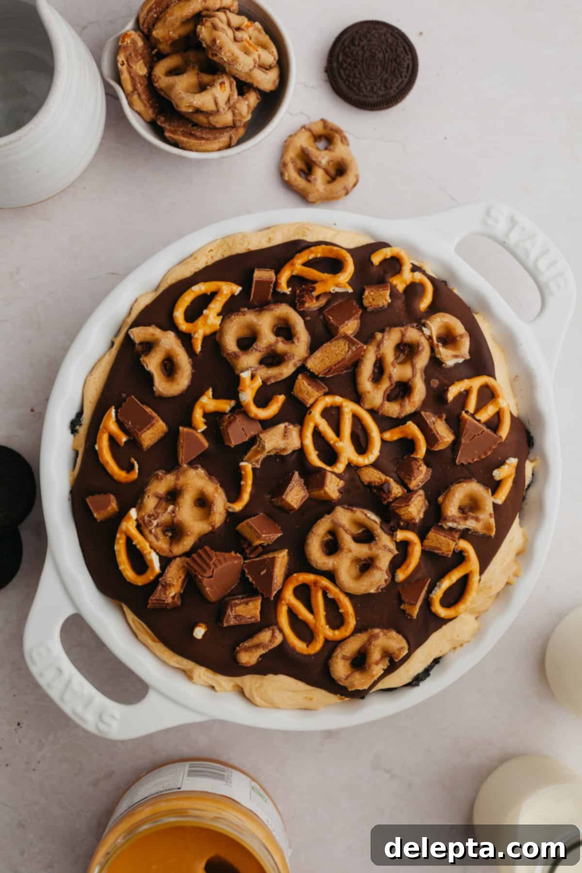 Decadent No-Bake Oreo Peanut Butter Pie 7 An overhead view of a beautifully prepared Oreo peanut butter pie, topped with chocolate ganache and crunchy pretzels, invitingly displayed in a pie dish.