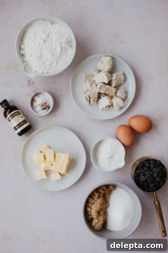 Halva Chocolate Chip Cookie Giants 2 Overhead view of ingredients for halva chocolate chip cookies laid out on a marble surface, including flour, sugars, eggs, butter, chocolate chips, and a block of halva.