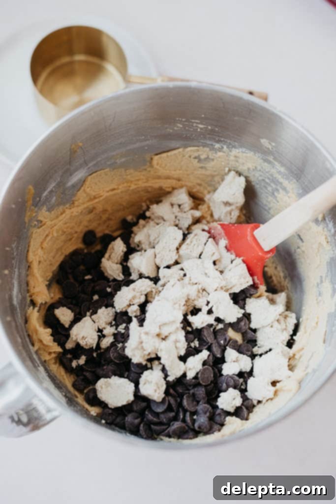 Halva Chocolate Chip Cookie Giants 5 Overhead view of cookie dough in a stand mixer bowl, with chocolate chips and chopped halva pieces folded in.
