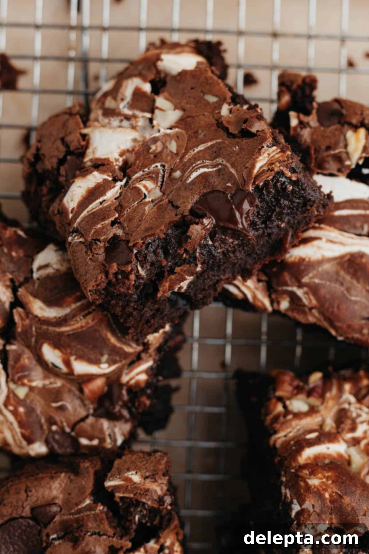 Swirled Marshmallow Dream Brownies 2 Marshmallow swirl brownies cooling on a wire rack, topped with chocolate chips and pecans.