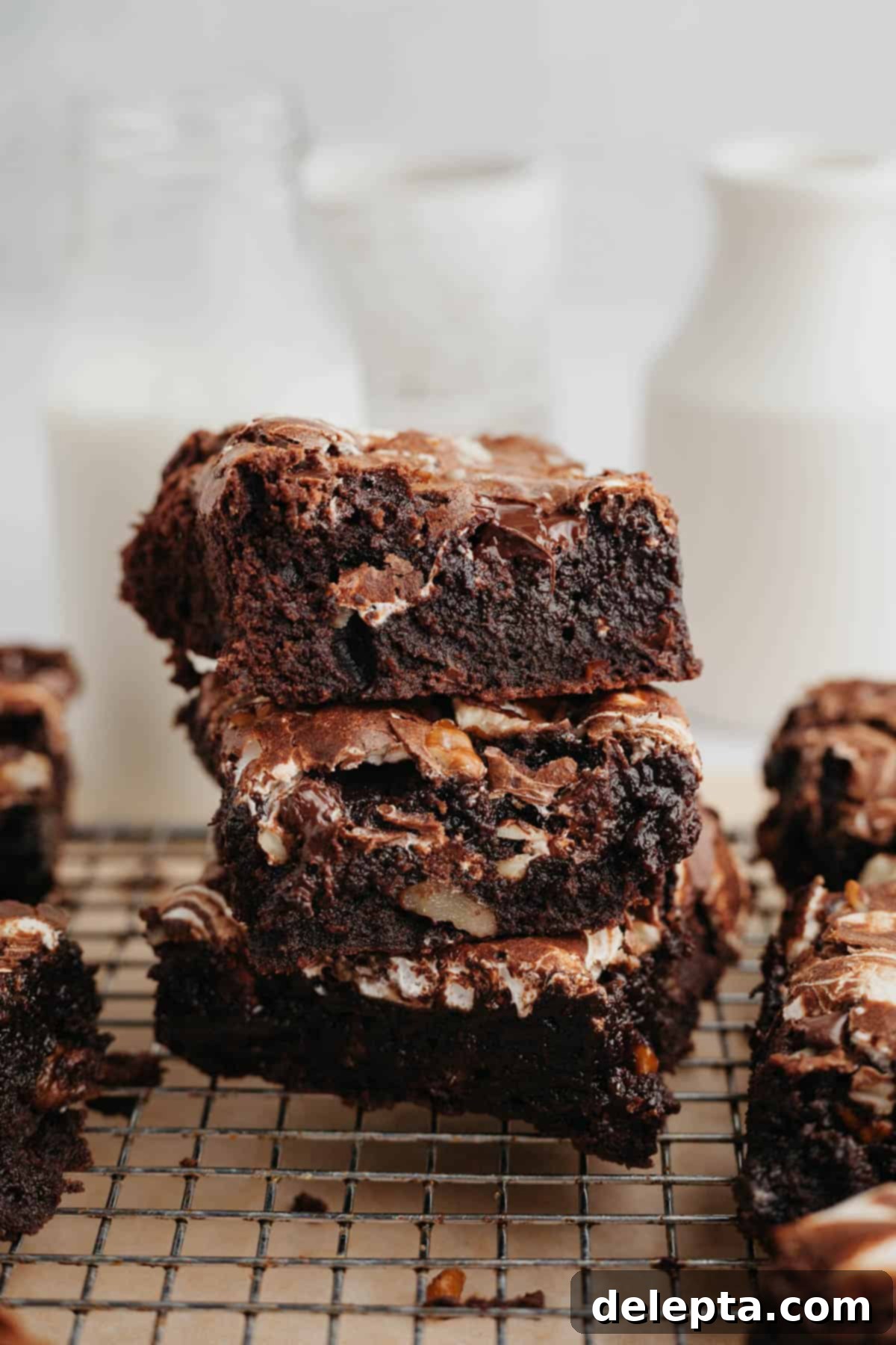 Swirled Marshmallow Dream Brownies 8 A stack of three rich, fudgy brownies with marshmallow fluff swirls on a wire cooling rack.