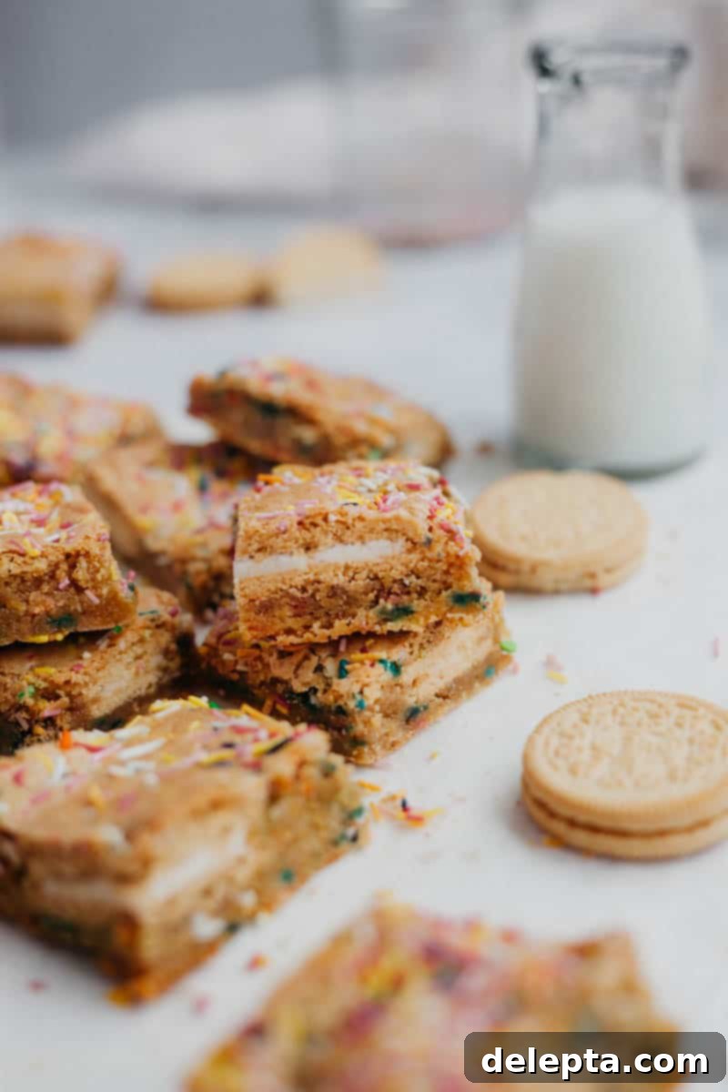 Sprinkle-Studded Golden Oreo Gooey Bars 12 A stack of freshly baked funfetti gooey bars, cut into perfect squares, with a small bottle of milk in the background, hinting at a delicious snack.