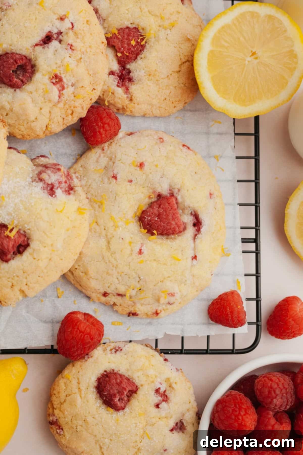 Easy One Bowl Lemon Raspberry Cookies 2 Lemon raspberry cookies on parchment paper. A close-up shot of perfectly baked cookies with visible raspberries and a sugary crust.