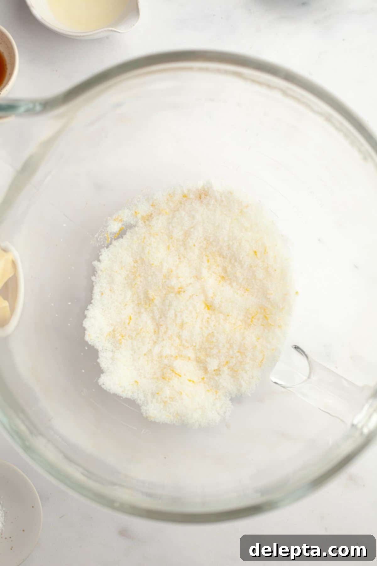 Easy One Bowl Lemon Raspberry Cookies 4 Lemon zest and sugar in a bowl. A hand is mixing them together.