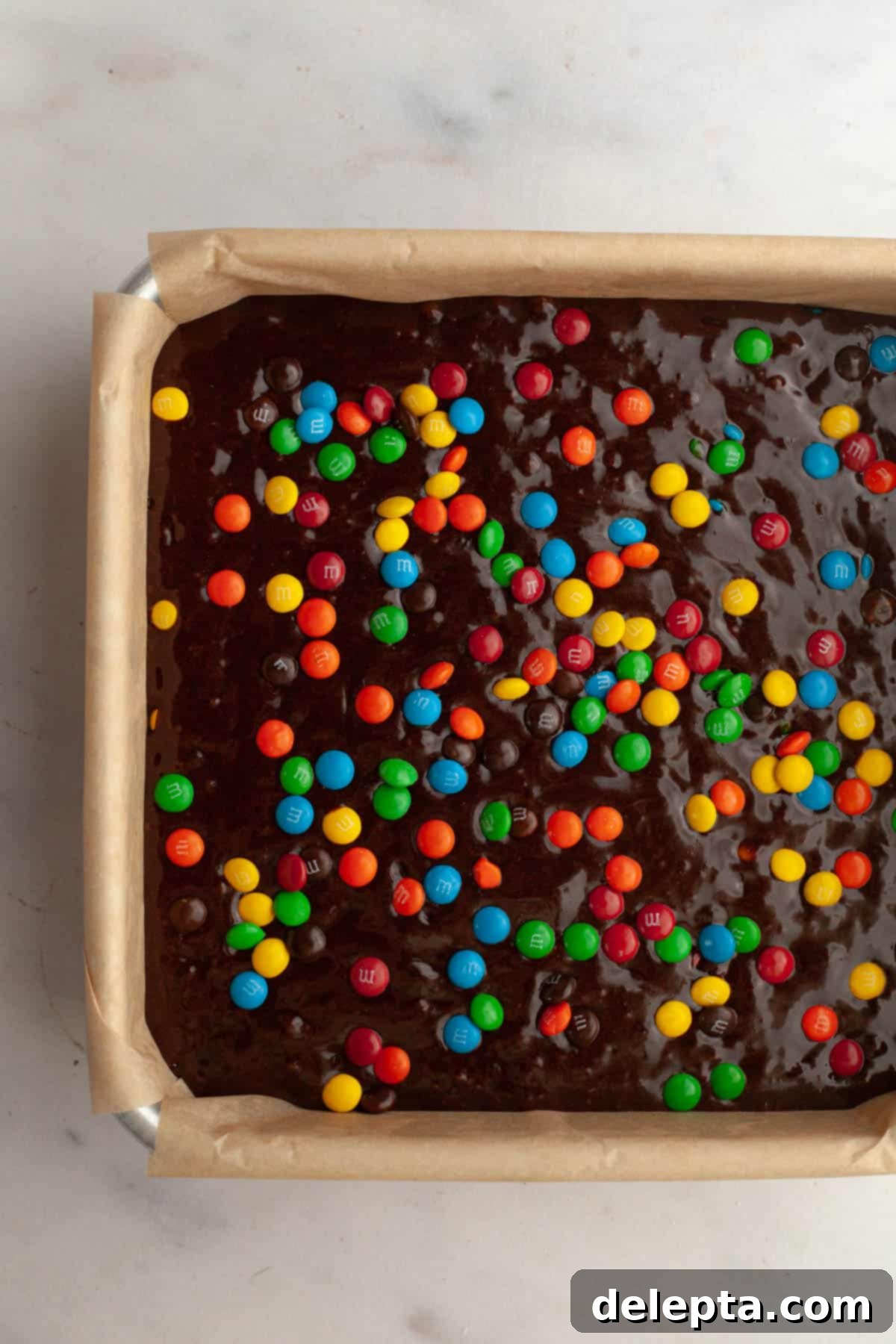 Fudgy M and M Brownies 9 Unbaked M&M brownies in a square baking pan.