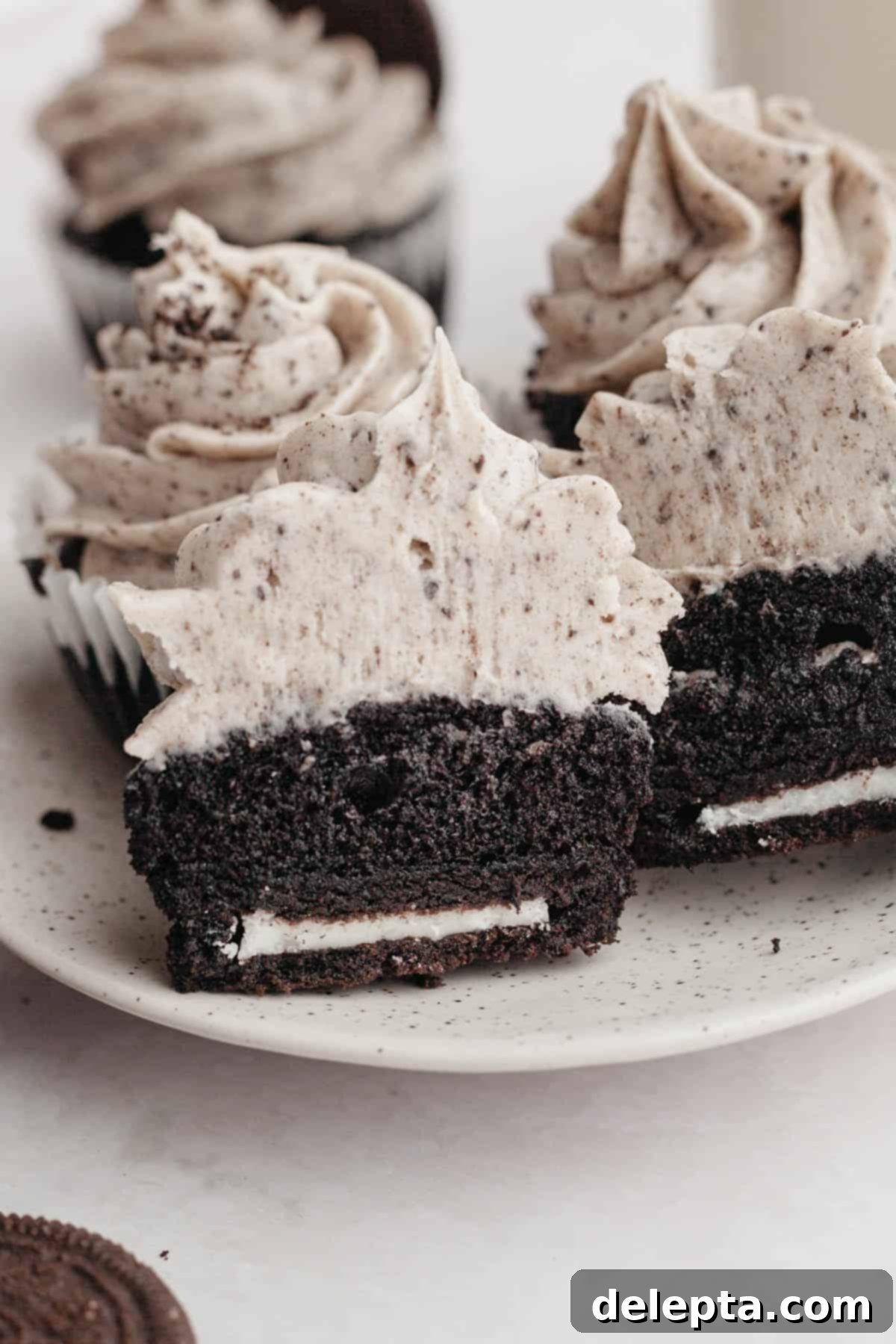 Decadent Chocolate Oreo Delights 9 A chocolate Oreo cupcake sliced in half, clearly showing it has a full Oreo cookie at the bottom, nestled in the cake.