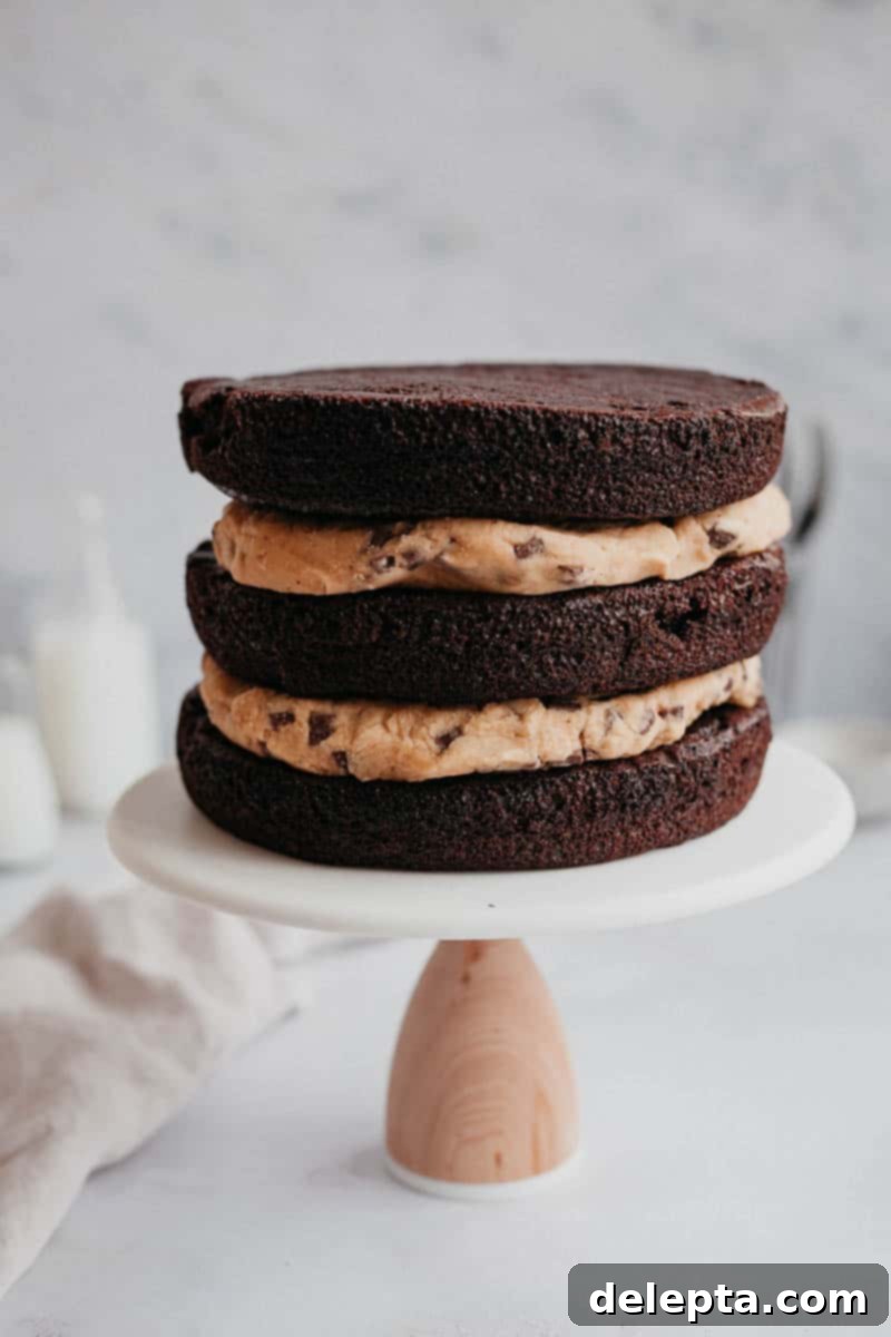 Chocolate Brownie Cookie Dough Fudge Cake 3 Brownie cake on a cake stand, unfrosted with a cookie dough filling