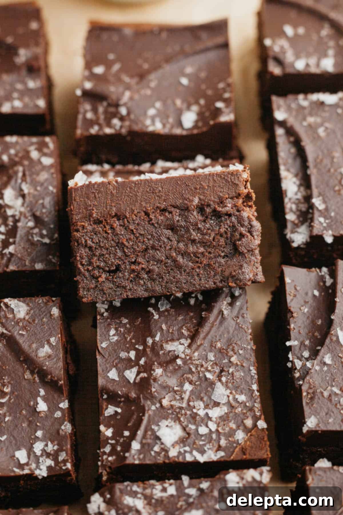 Decadent Fudgy Brownies with Velvety Chocolate Ganache 2 Close-up of fudgy brownies with chocolate ganache and sea salt on a white plate