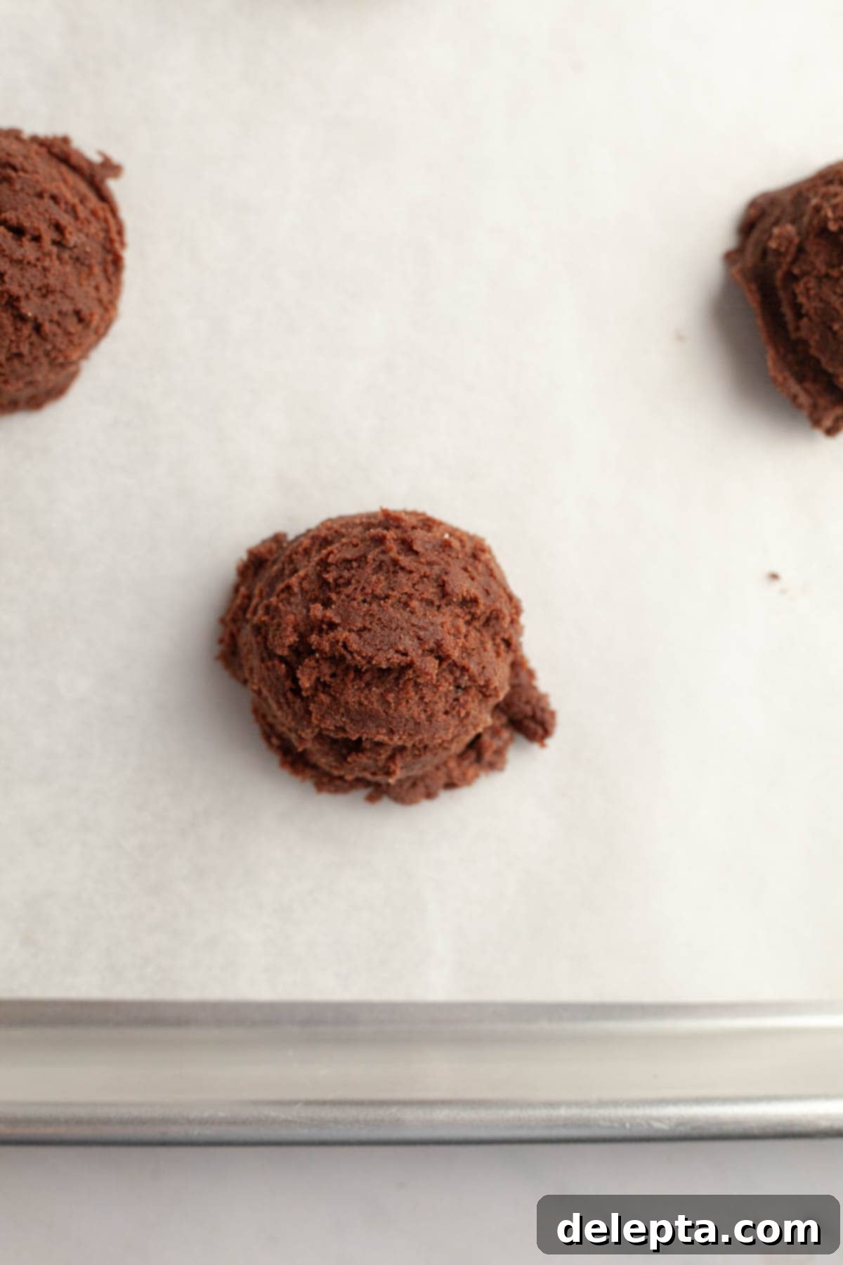 Galaxy Brownie Cookies 6 Uniform chocolate cookie dough balls neatly arranged on parchment paper-lined baking sheets.