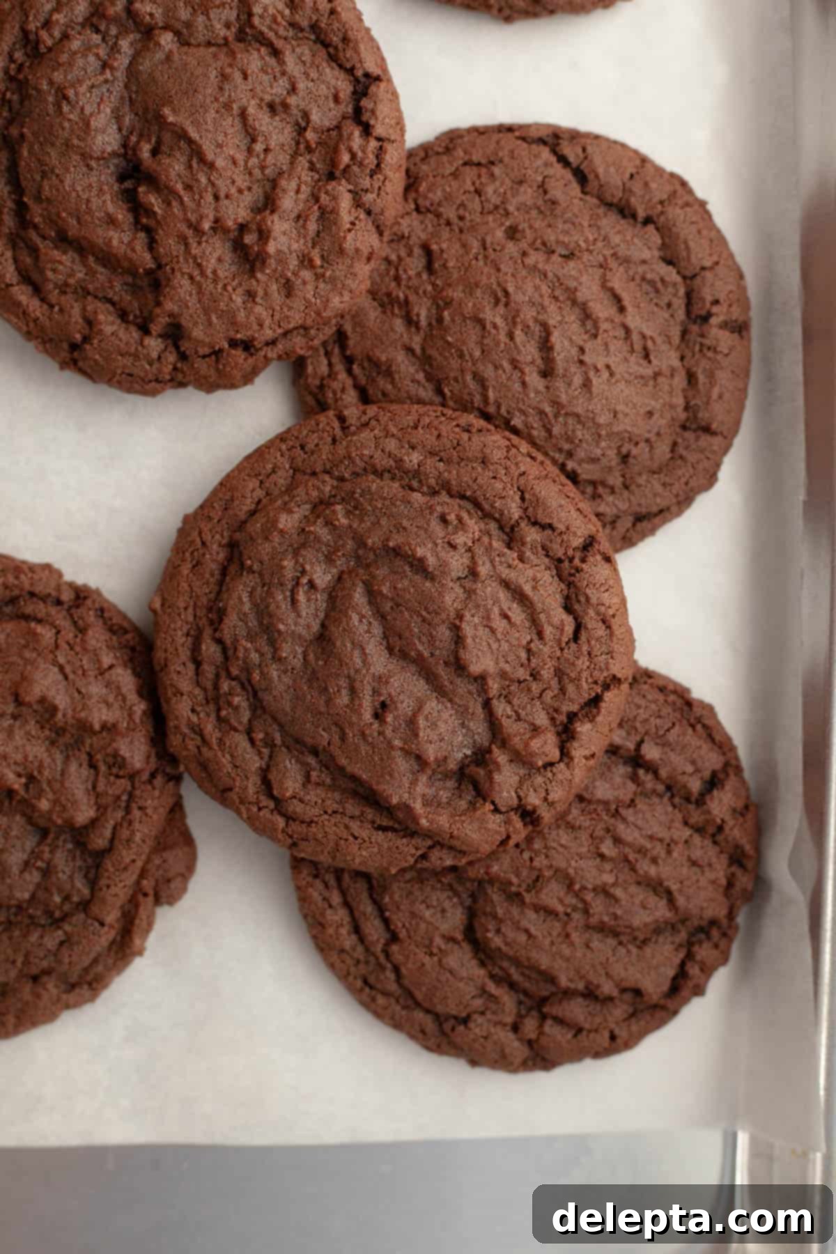 Galaxy Brownie Cookies 7 Freshly baked chocolate cookies with slightly cracked tops cooling on parchment paper.