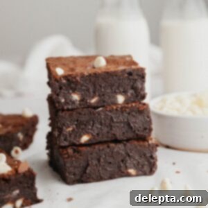 Effortlessly Fudgy White Chocolate Chip Brownies 10 A stack of three brownies with white chocolate chips.