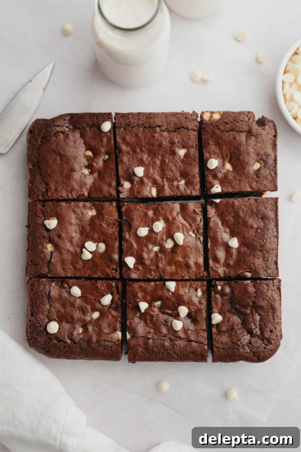 Effortlessly Fudgy White Chocolate Chip Brownies 8 A batch of baked white chocolate chip brownies, cut into neat squares and arranged on a cooling rack, ready to be enjoyed.