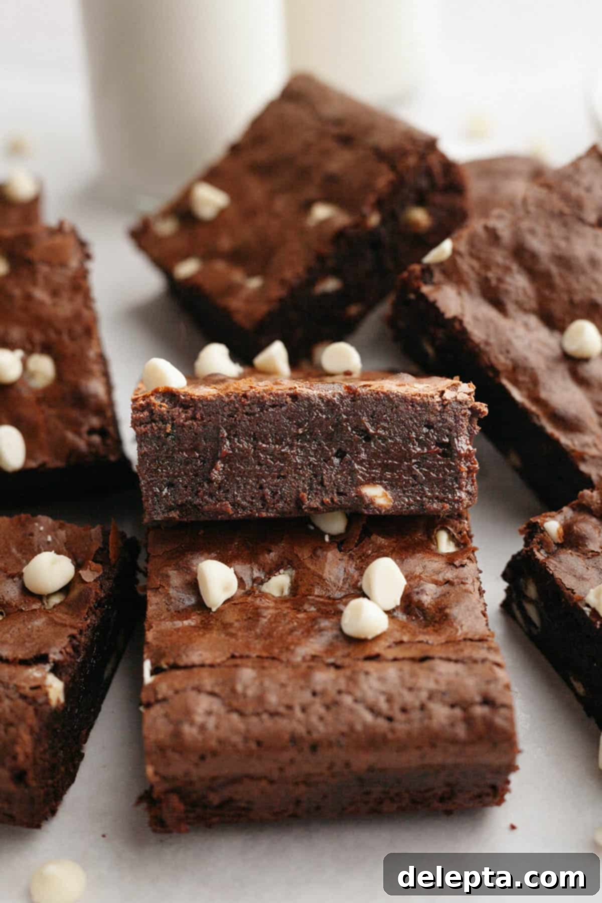 Effortlessly Fudgy White Chocolate Chip Brownies 9 A close-up shot of perfectly sliced white chocolate chip brownies, artfully arranged on parchment paper, highlighting their fudgy interior and speckled white chocolate.