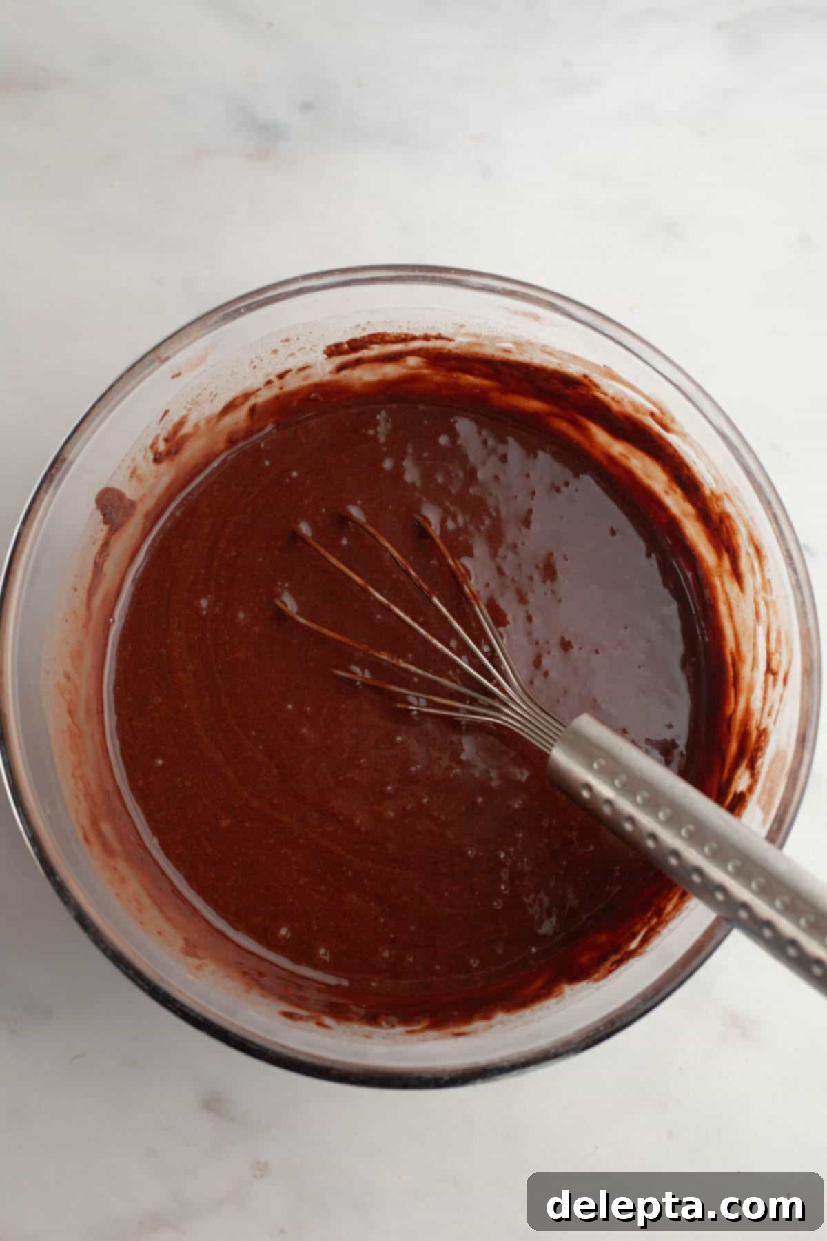 Decadent Chocolate Cream Cheese Cupcakes 6 A large glass bowl with chocolate cake batter in it and a whisk, showing the smooth batter.