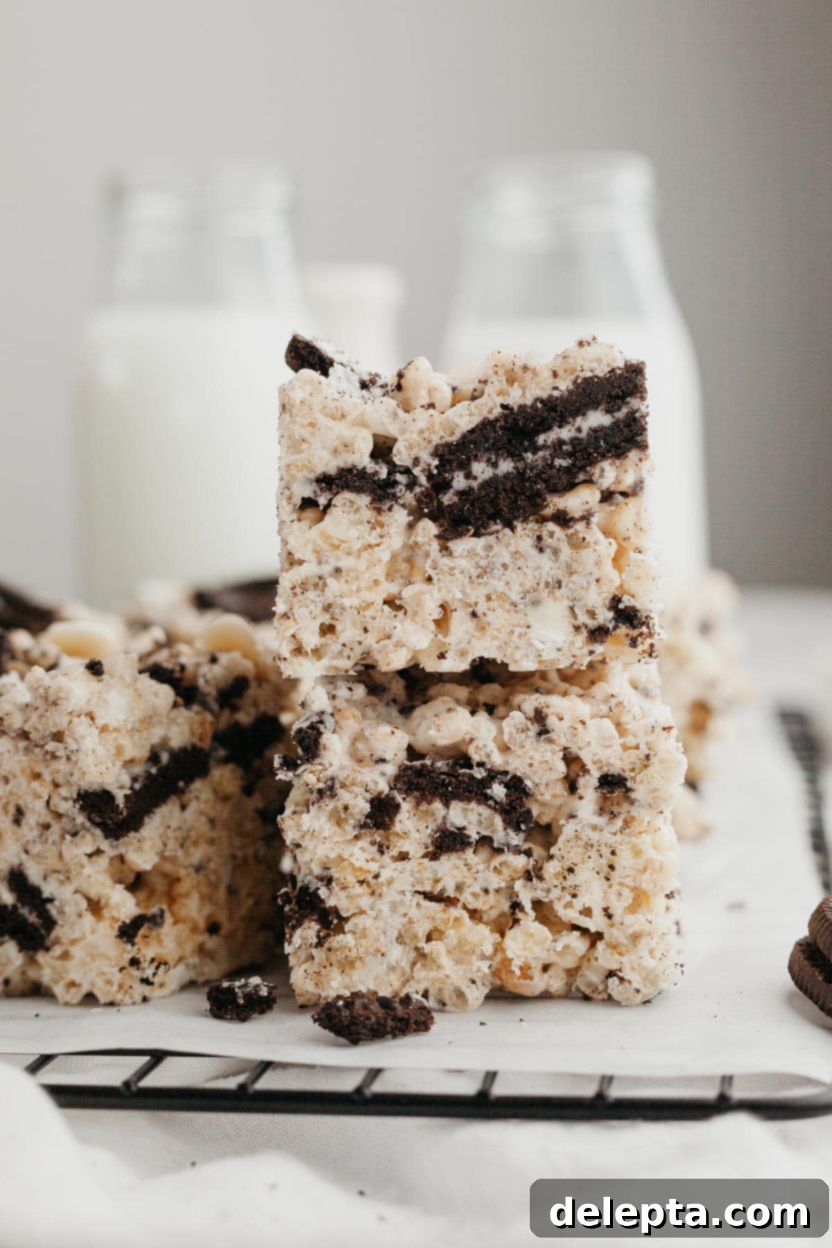 Cookies and Cream Krispie Bars 2 A stack of two perfectly cut, gooey Oreo Rice Krispie Treats, showcasing the crushed cookies and white chocolate chips within.