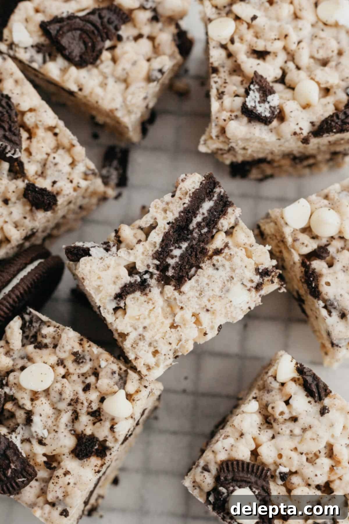 Cookies and Cream Krispie Bars 7 A perfectly cut block of Oreo Rice Krispie Treats resting on parchment paper, ready to be sliced into individual bars.