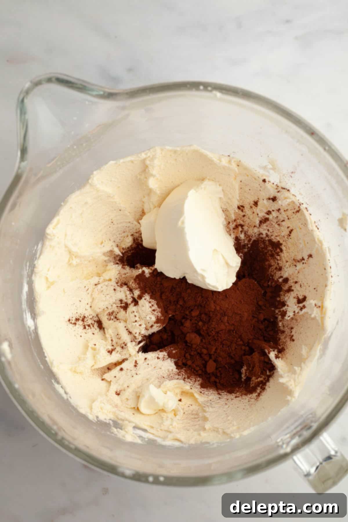 Irresistible Mini Chocolate Cupcakes: Effortlessly Moist Perfection 8 A large mixing bowl with creamed butter in it and cocoa powder and cream cheese.