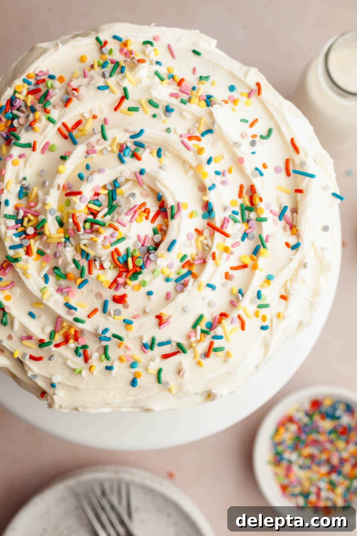 Foolproof Chocolate Cake with Sweet Vanilla Frosting 10 An overhead shot of a vanilla frosted cake with rainbow sprinkles, showcasing the final beautiful decoration.