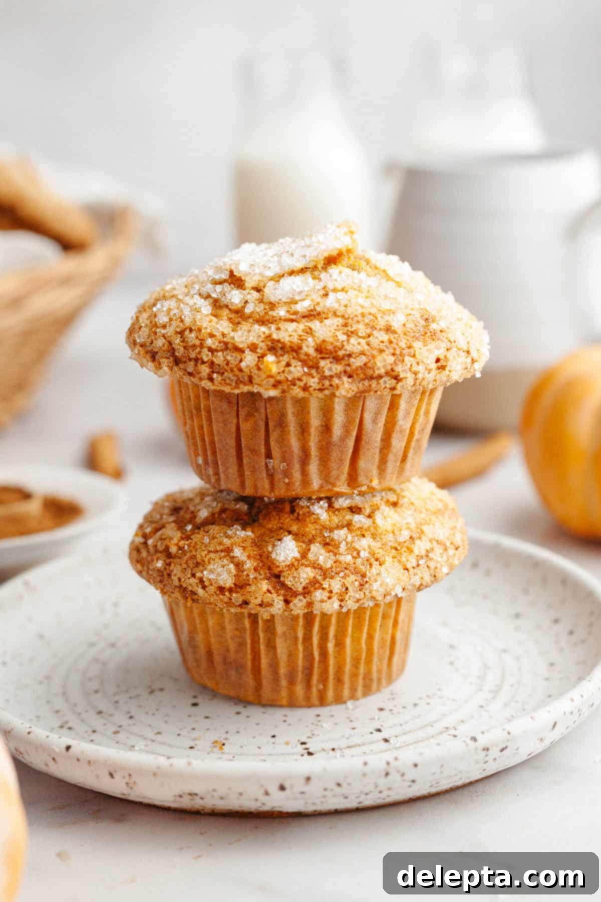 Effortlessly Moist Pumpkin Banana Muffins 2 Two pumpkin banana muffins stacked on top of each other, on a plate.