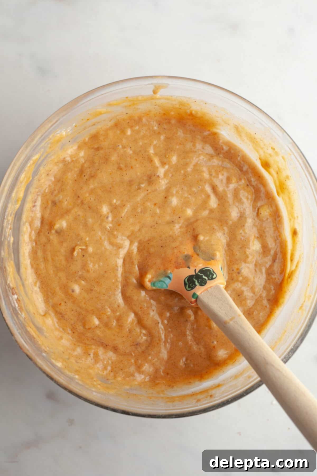 Effortlessly Moist Pumpkin Banana Muffins 5 Pumpkin banana muffin mixture in a bowl with a rubber spatula.