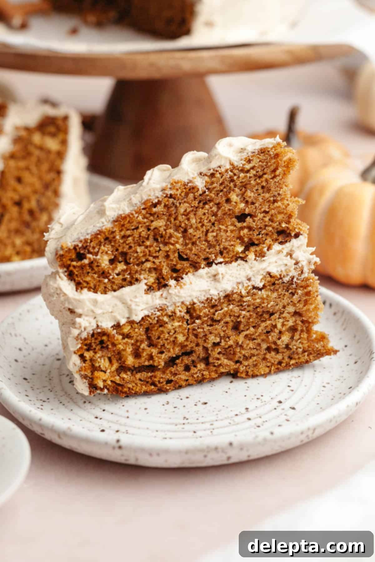 Pumpkin Spiced Latte Cake Bake 2 A beautifully plated slice of pumpkin spice latte cake, featuring distinct layers of moist pumpkin cake and creamy coffee frosting, ready to be enjoyed.