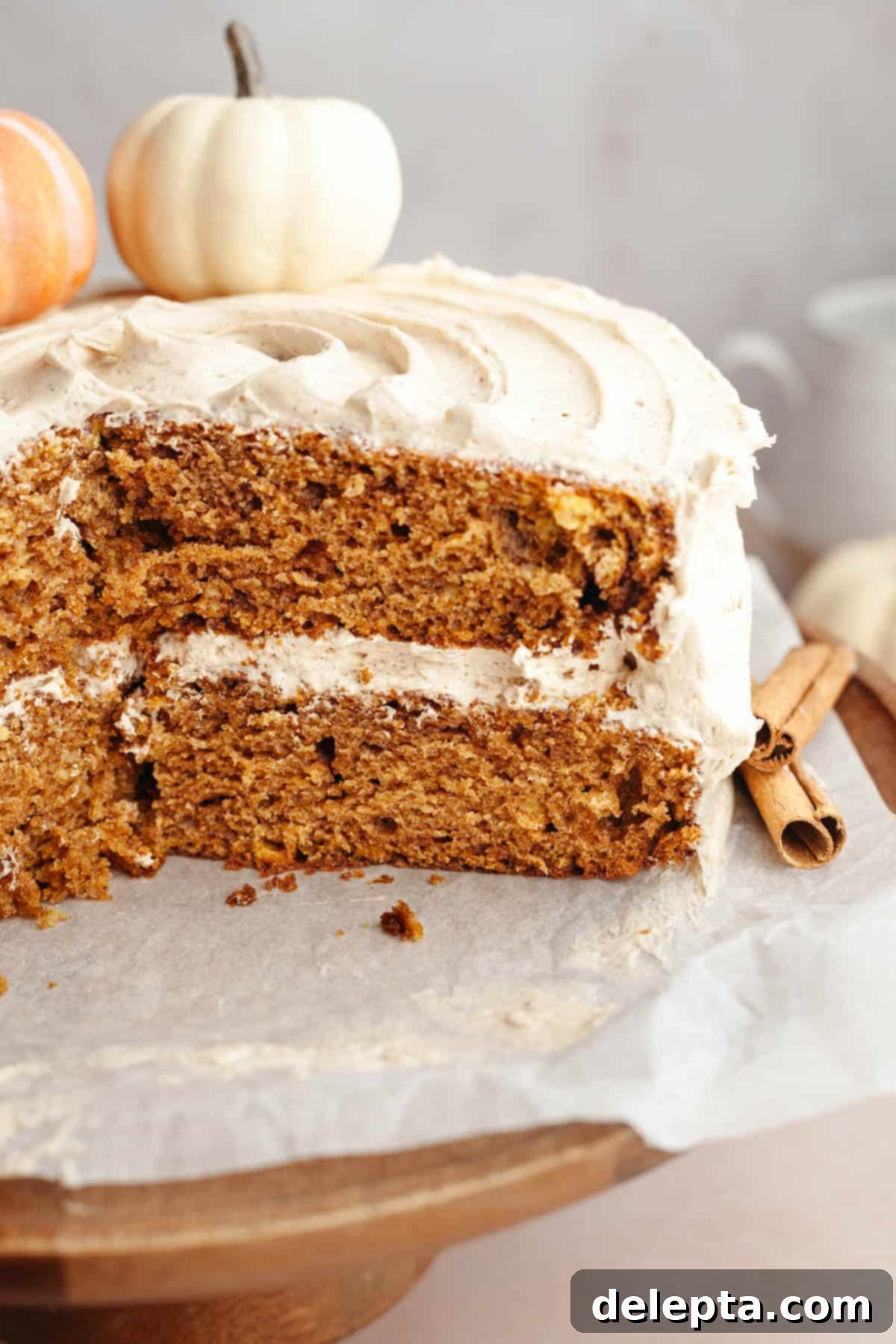 Pumpkin Spiced Latte Cake Bake 10 A close-up view of a Pumpkin Spice Latte Cake on a rustic wooden cake stand, with a slice already cut, revealing the moist cake layers and creamy frosting.