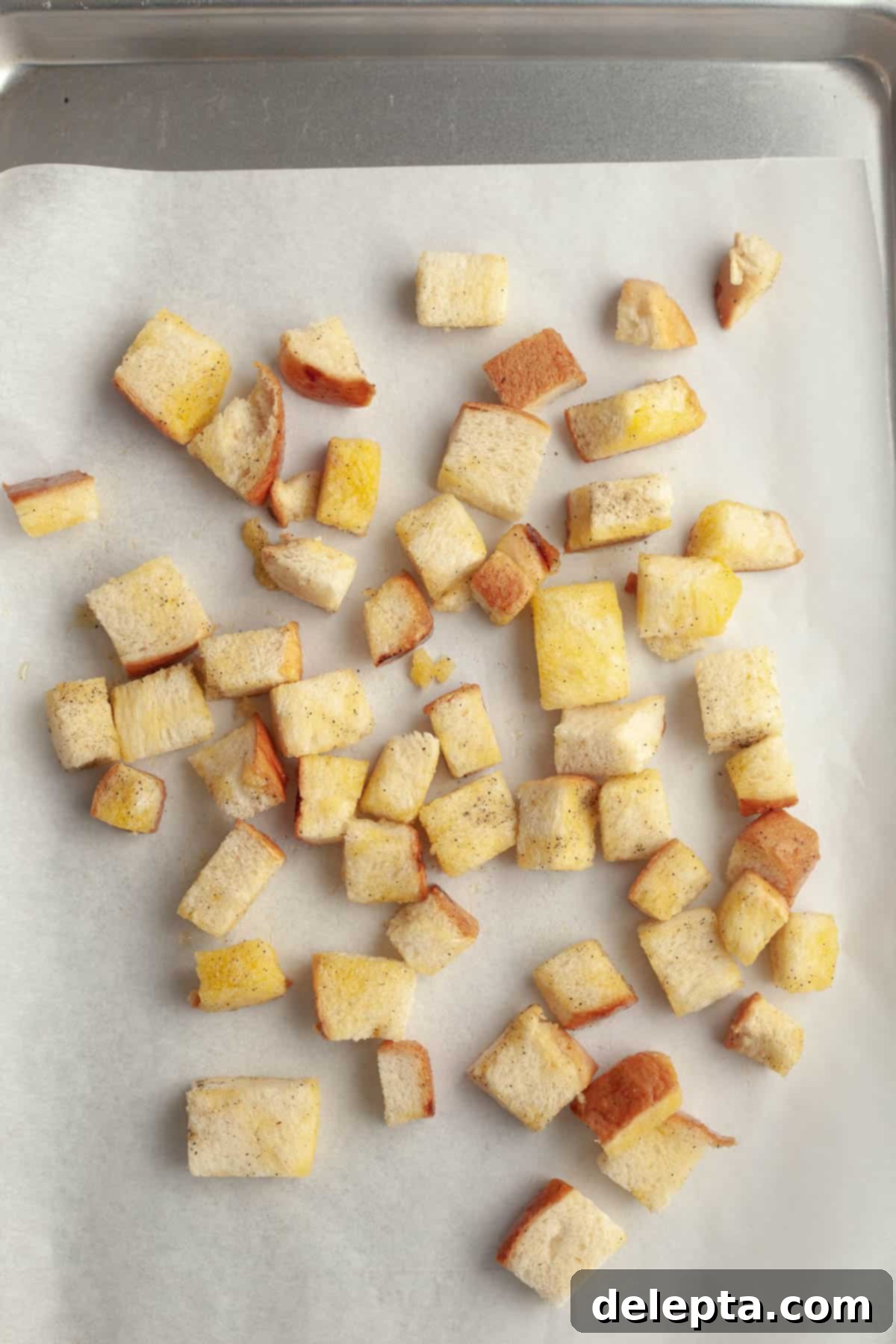 Whip Up Perfect Brioche Croutons at Home 5 Cubed brioche bread, now tossed in olive oil and seasoning, spread out on a baking sheet, ready for the oven.