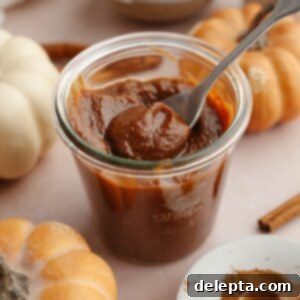 Easy Homemade Pumpkin Spice Syrup 9 Pumpkin sauce in a glass jar with a spoon.