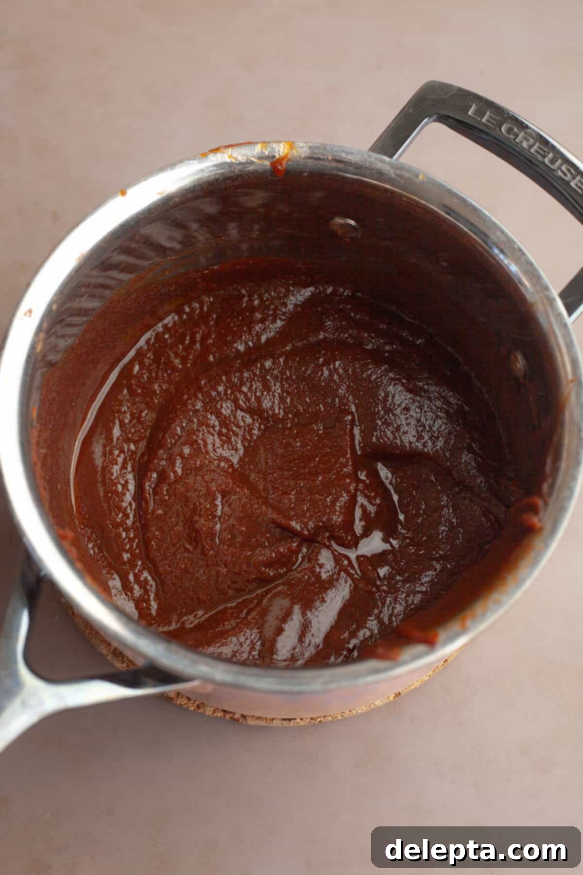 Easy Homemade Pumpkin Spice Syrup 6 A silver saucepan with the thickened pumpkin sauce for coffee, just removed from heat.