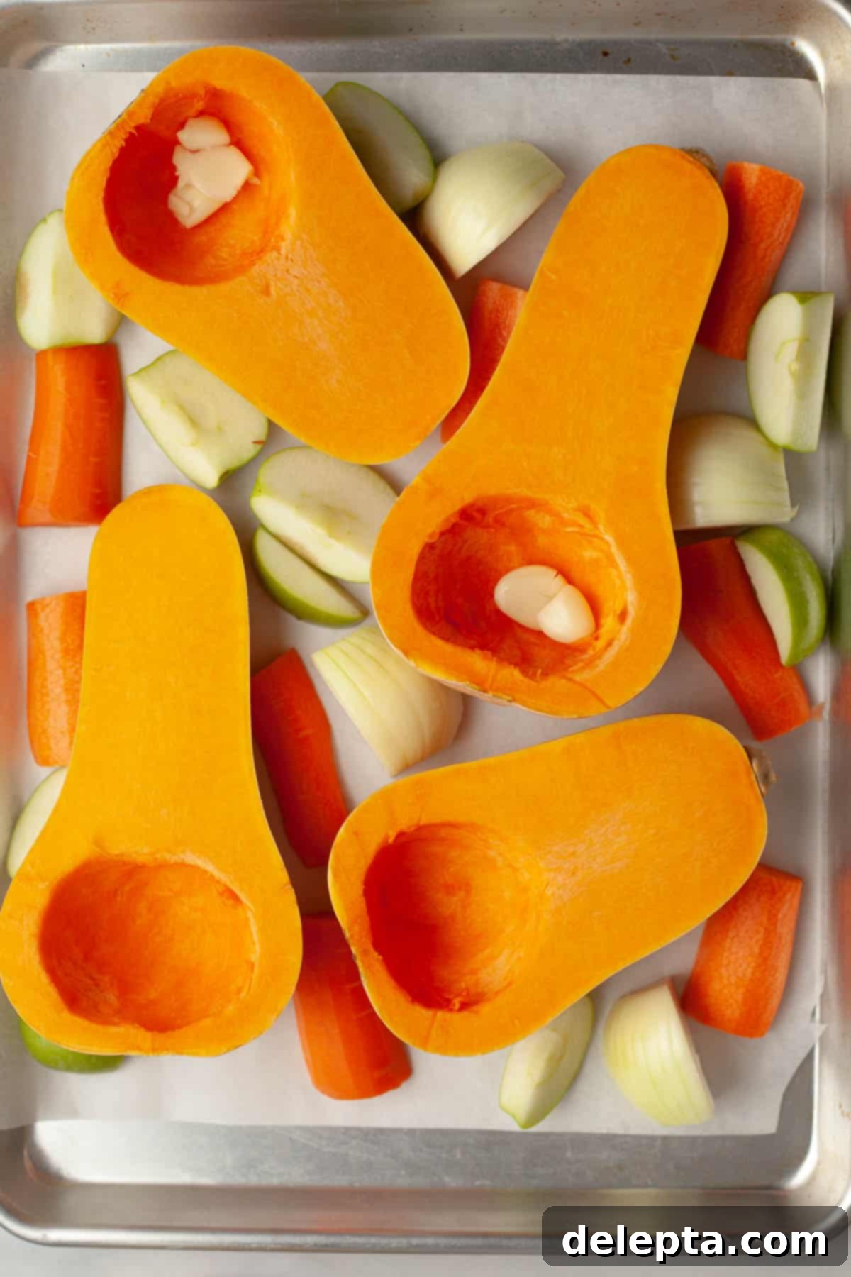 Autumn Gold Roasted Butternut Chicken Soup 4 A sheet pan loaded with halved butternut squash, chopped carrots, quartered apples, and onion wedges, ready for roasting.