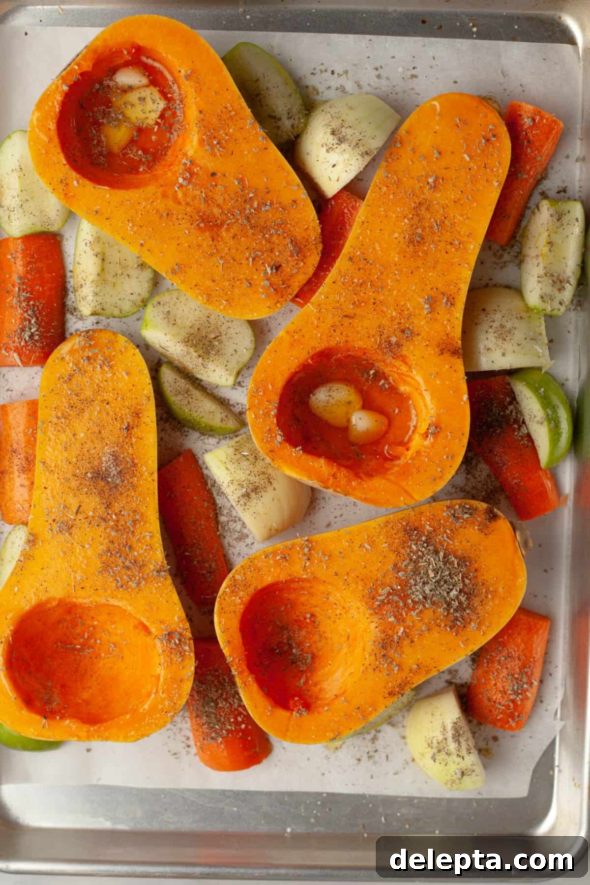 Autumn Gold Roasted Butternut Chicken Soup 5 A sheet pan with butternut squash halves, carrots, onion, and apples, all brushed with oil and seasoned before roasting.