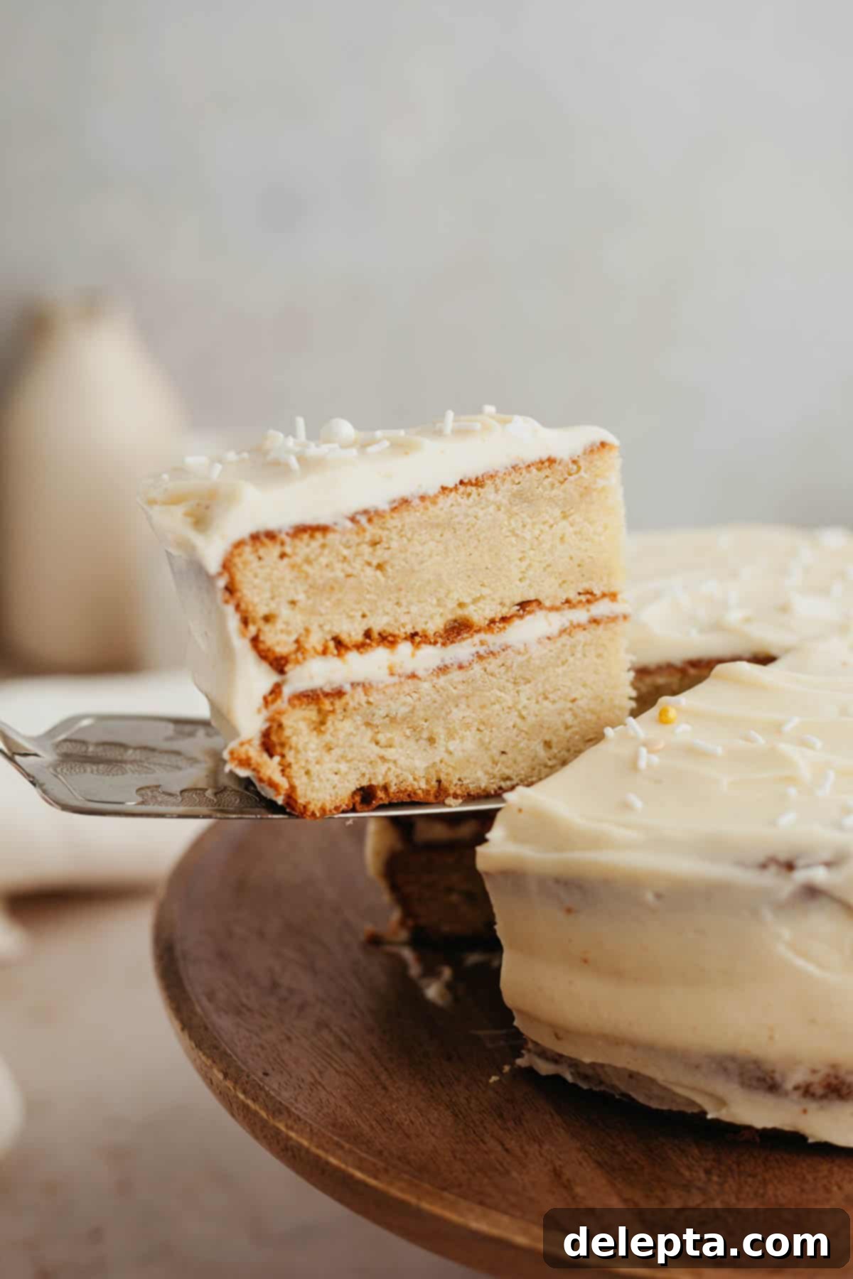 Brown Butter Cream Cheese Cardamom Cake 2 A silver serving knife lifting up a slice of cardamom cake, revealing its moist texture and creamy frosting.