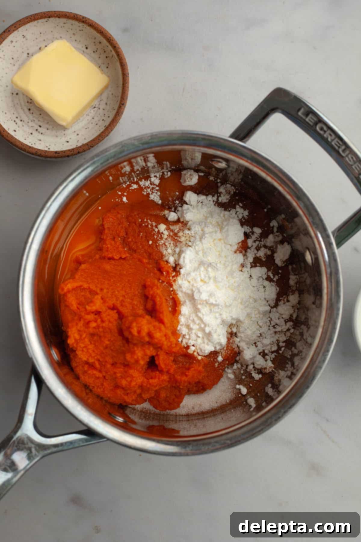 Effortless No Bake Pumpkin Delights 4 A medium saucepan containing a vibrant orange mixture of pumpkin puree, cornstarch, and other dry ingredients, ready to be whisked.