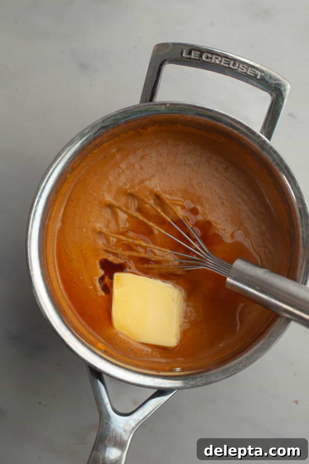 Effortless No Bake Pumpkin Delights 7 The thickened pumpkin pudding in a saucepan, with cubes of butter ready to be whisked in.