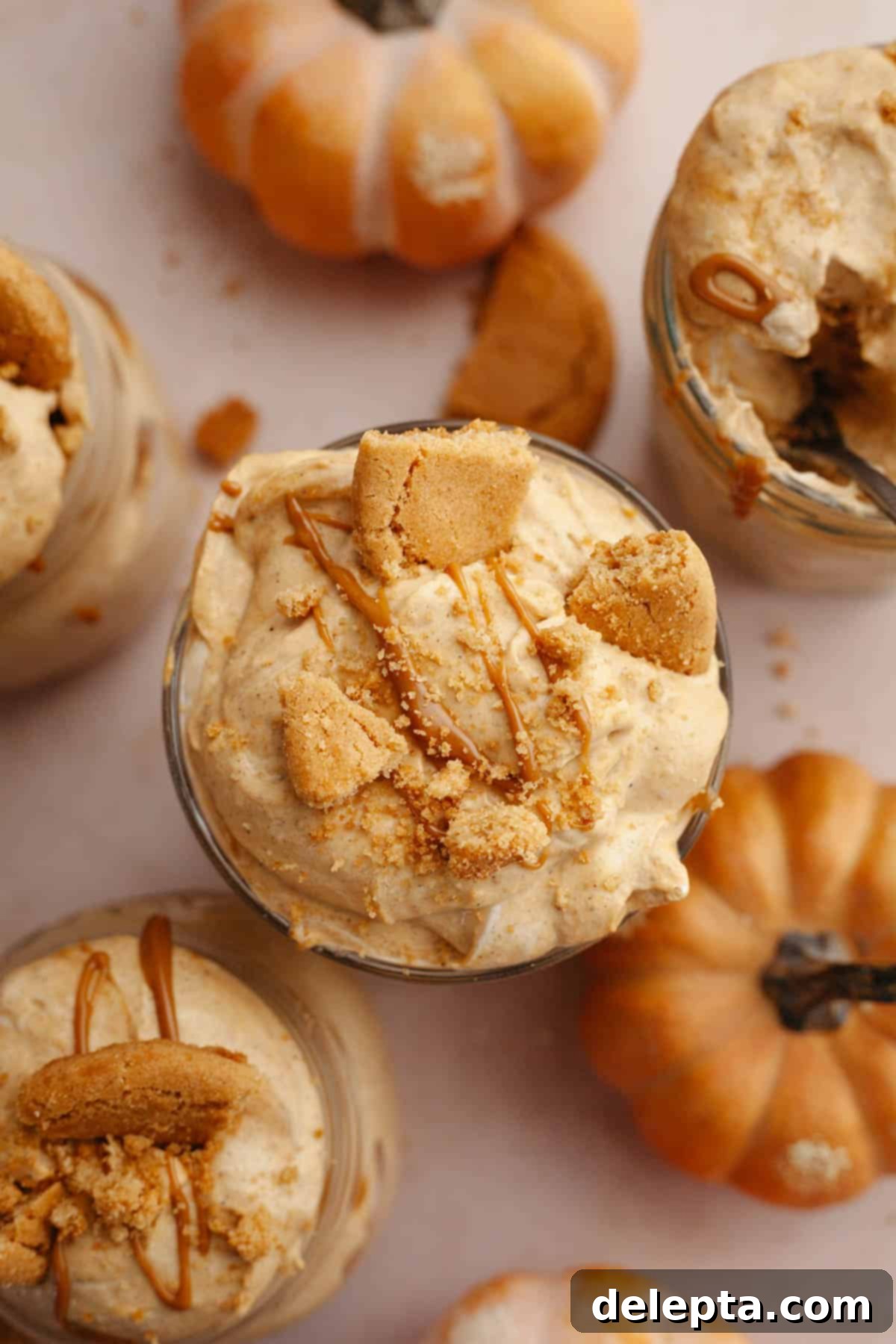 Effortless No Bake Pumpkin Delights 10 An overhead shot showcasing beautifully assembled pumpkin pudding cups in jars, garnished with a sprinkle of crushed gingersnap cookies and a delightful swirl of cookie butter.
