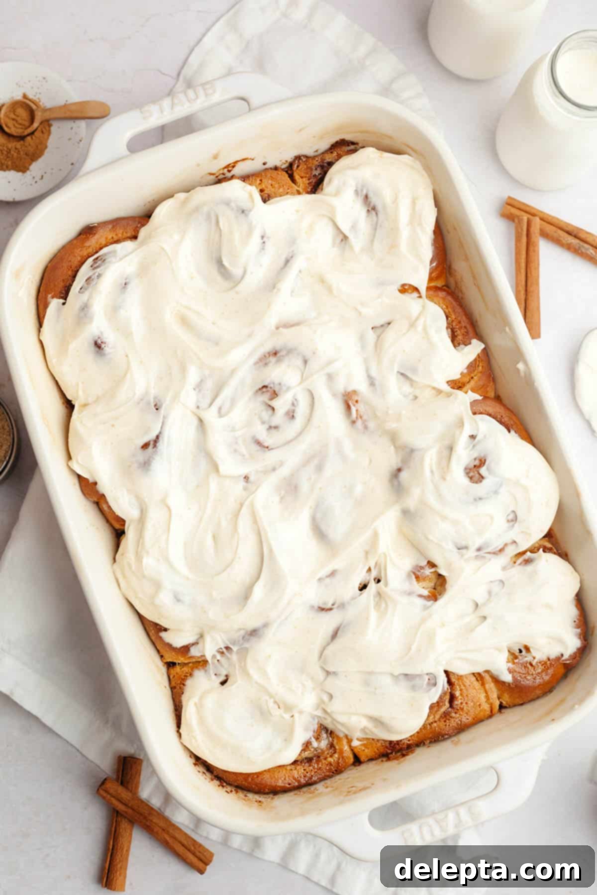 Rich Brown Butter Cinnamon Rolls with Velvety Brown Butter Frosting 2 Brown butter cinnamon rolls covered in brown butter frosting in a white baking dish.