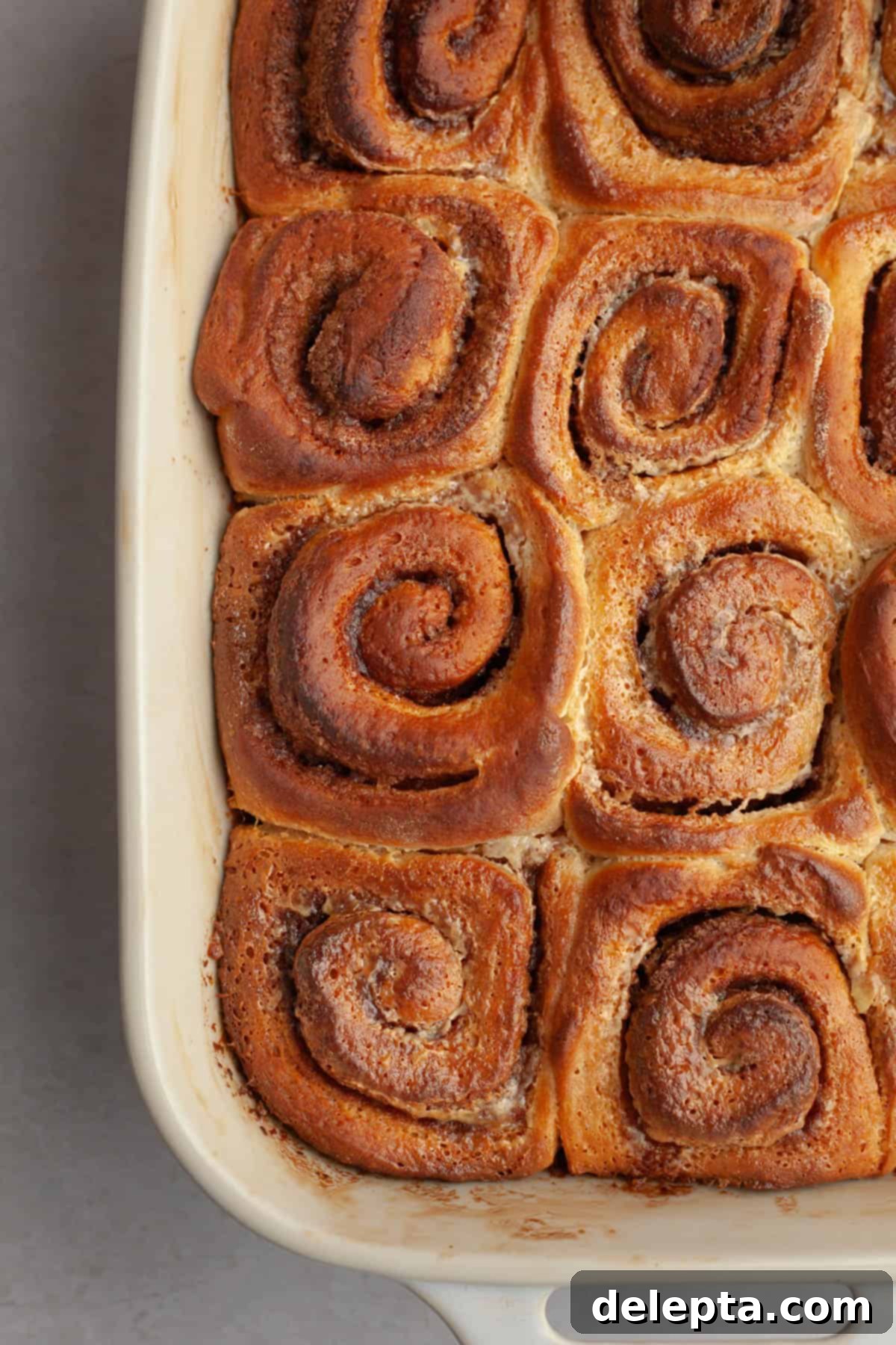 Rich Brown Butter Cinnamon Rolls with Velvety Brown Butter Frosting 12 Baked brown butter cinnamon rolls in a white baking dish.