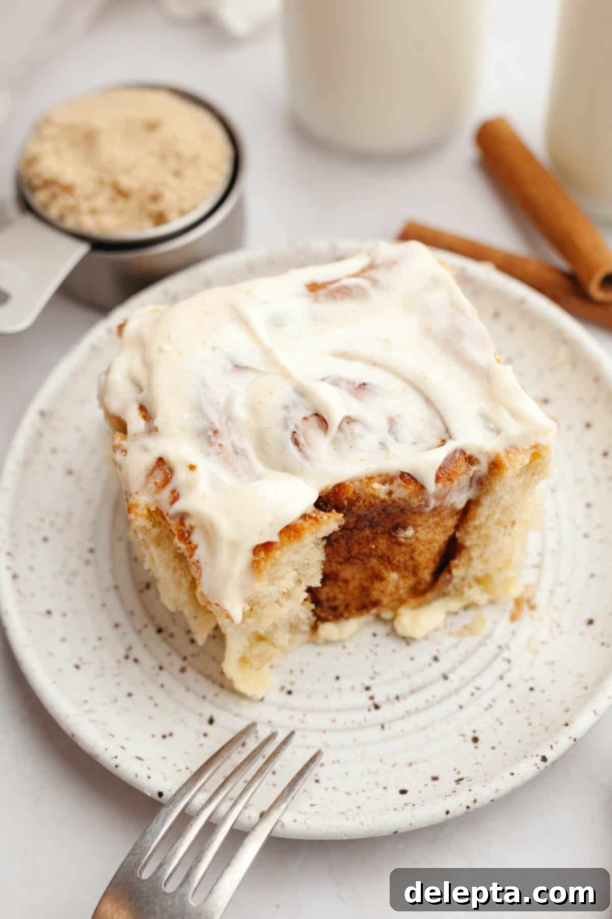 Rich Brown Butter Cinnamon Rolls with Velvety Brown Butter Frosting 14 A brown butter cinnamon roll covered in brown butter cream cheese frosting on a small plate.