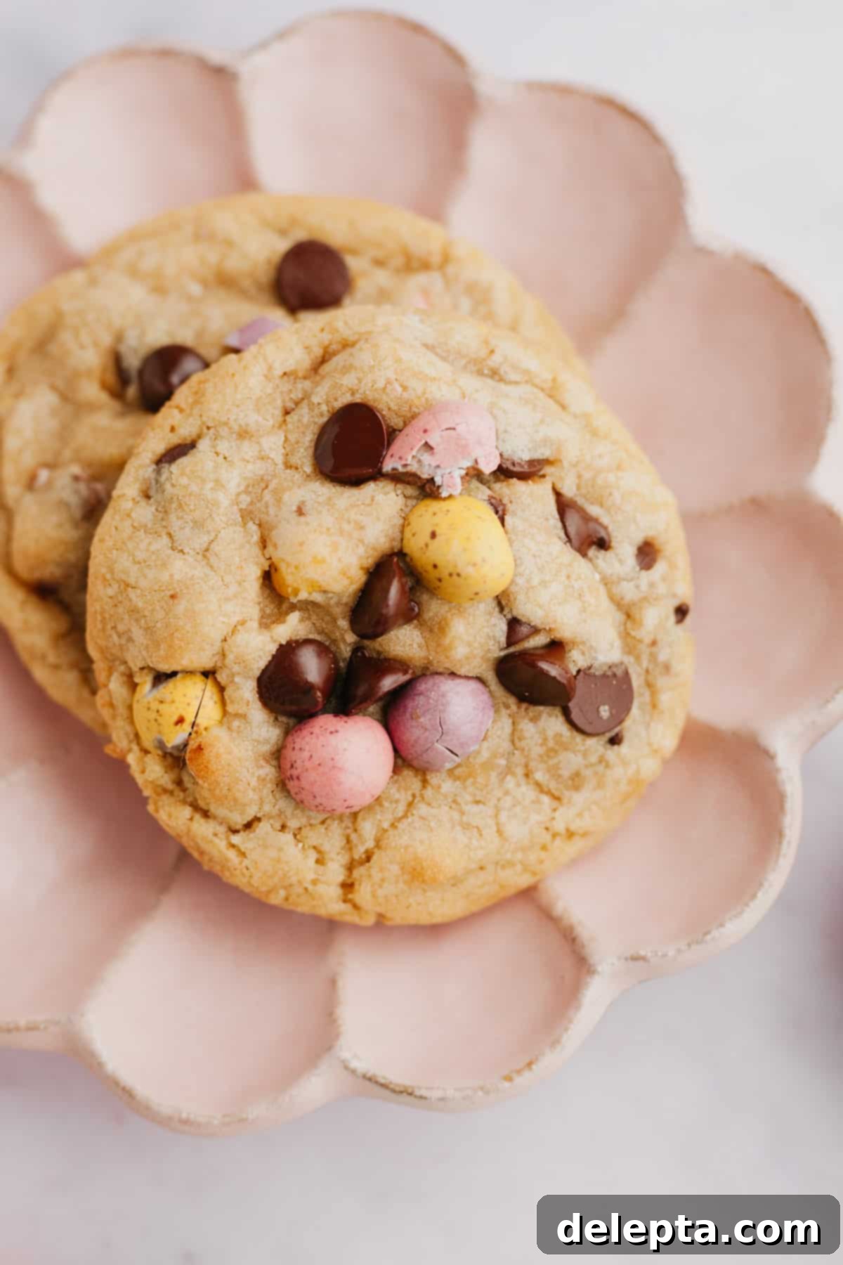 The Ultimate One Bowl Soft and Chewy Mini Egg Cookies 8 Two soft and chewy brown butter mini egg chocolate chip cookies on a small pink plate, ready to be enjoyed.