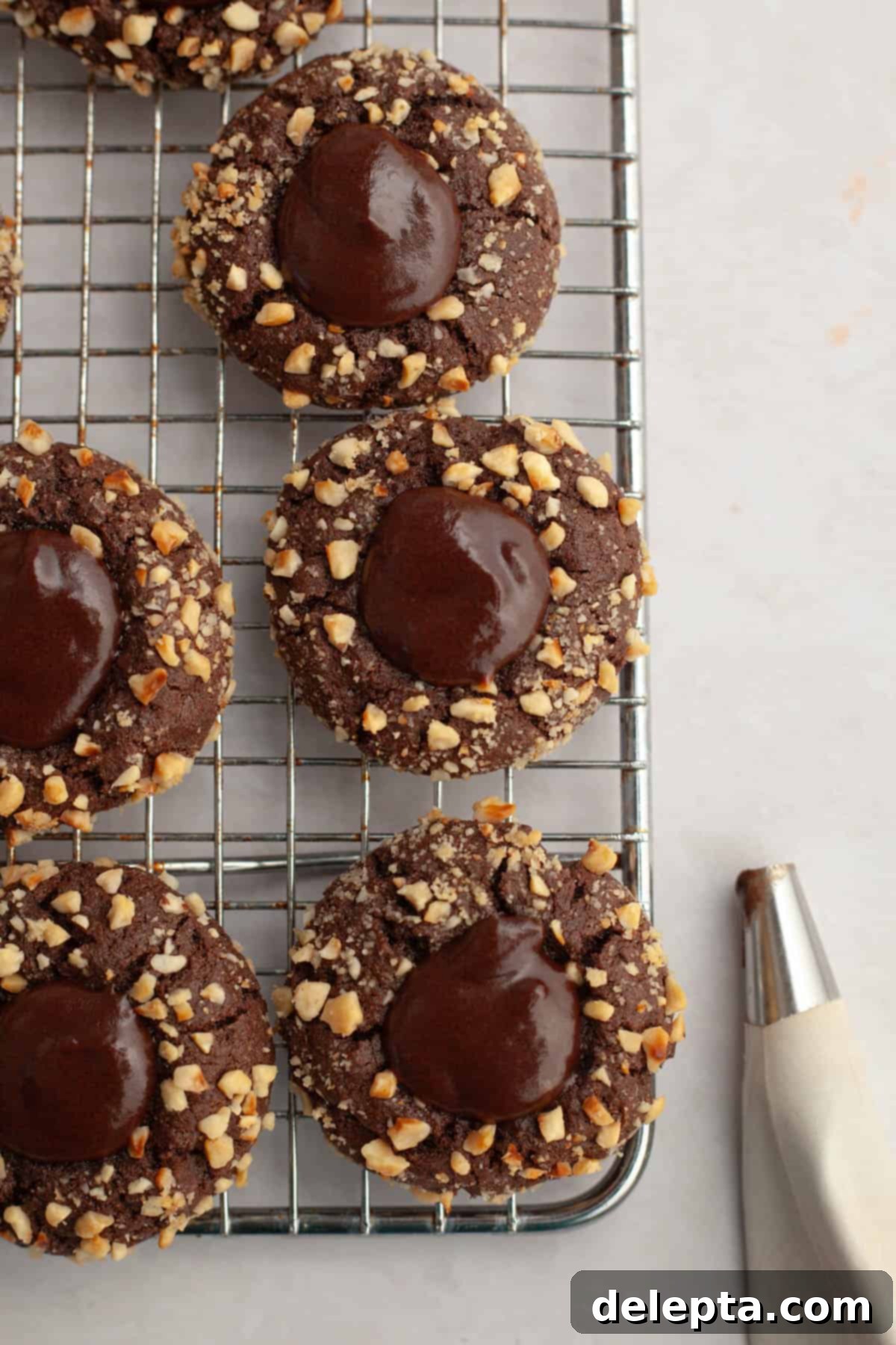 Double Nutella Bliss: Easy Thumbprint Cookies with Ganache 11 Nutella thumbprint cookies with ganache cooling on a wire rack.