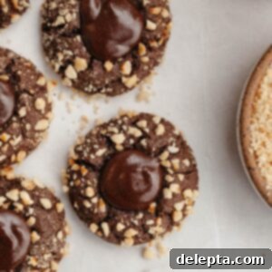 Double Nutella Bliss: Easy Thumbprint Cookies with Ganache 14 Nutella thumbprint cookies covered in chopped hazelnuts, ready to be enjoyed.