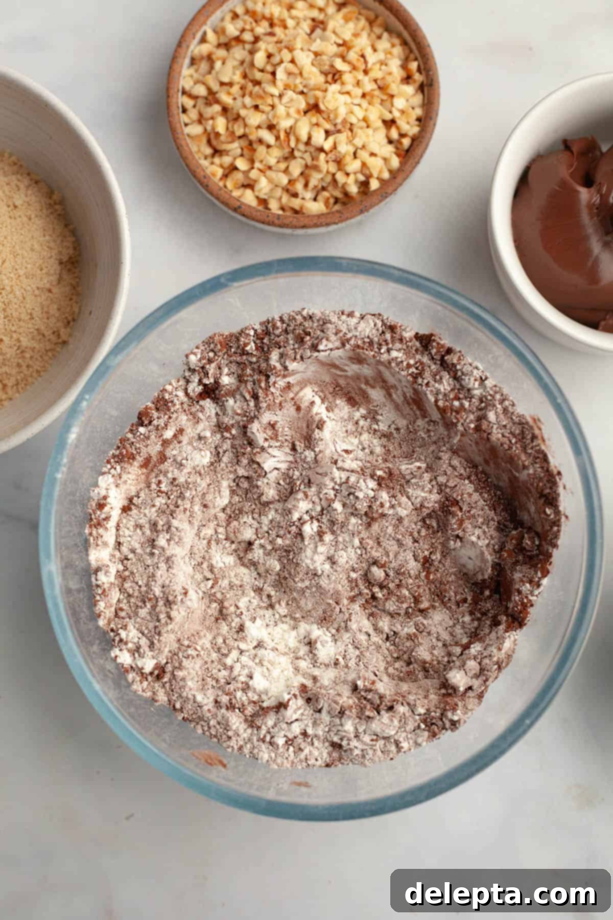 Double Nutella Bliss: Easy Thumbprint Cookies with Ganache 4 A large glass bowl with flour and cocoa powder mixed in, ready for the wet ingredients.