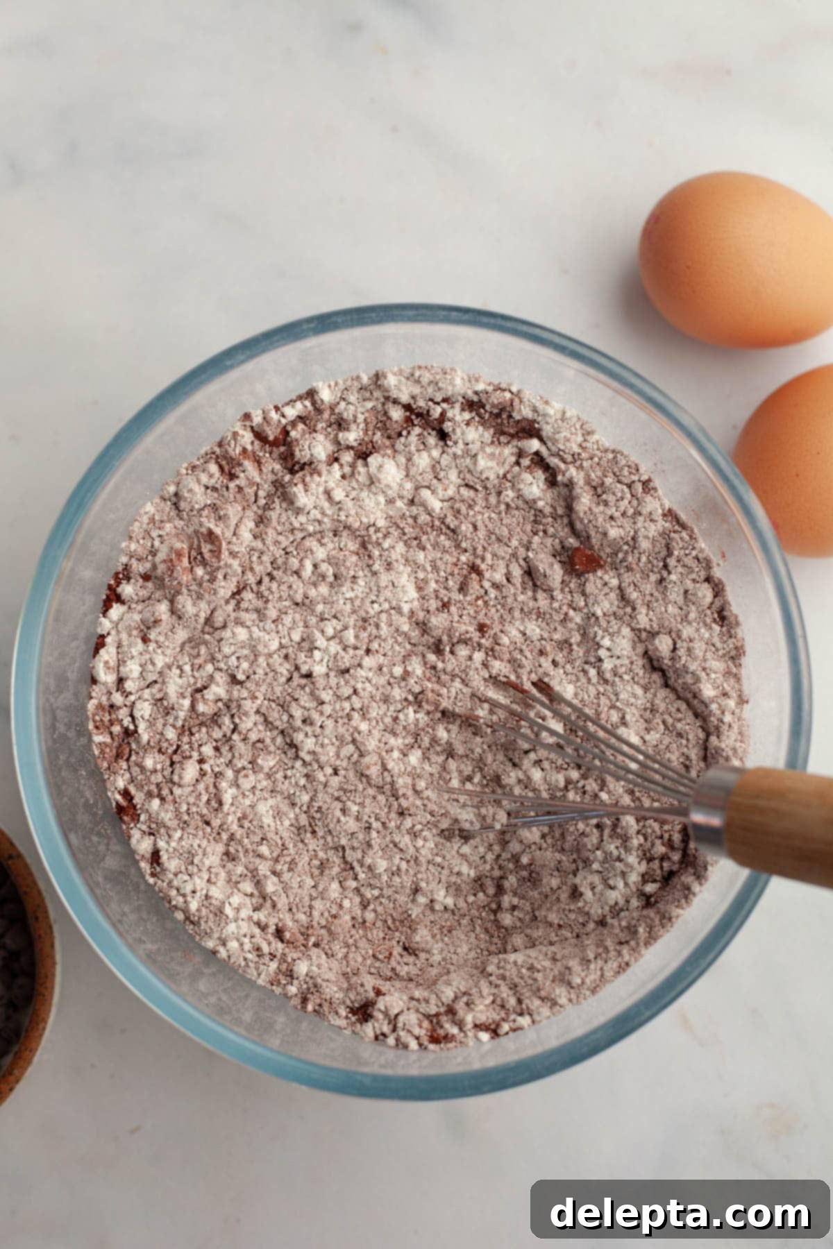 Red Velvet Chocolate Chip Indulgence 4 A medium glass bowl containing a perfectly whisked mixture of white flour and dark cocoa powder, ready for the next step of baking the red velvet cake.