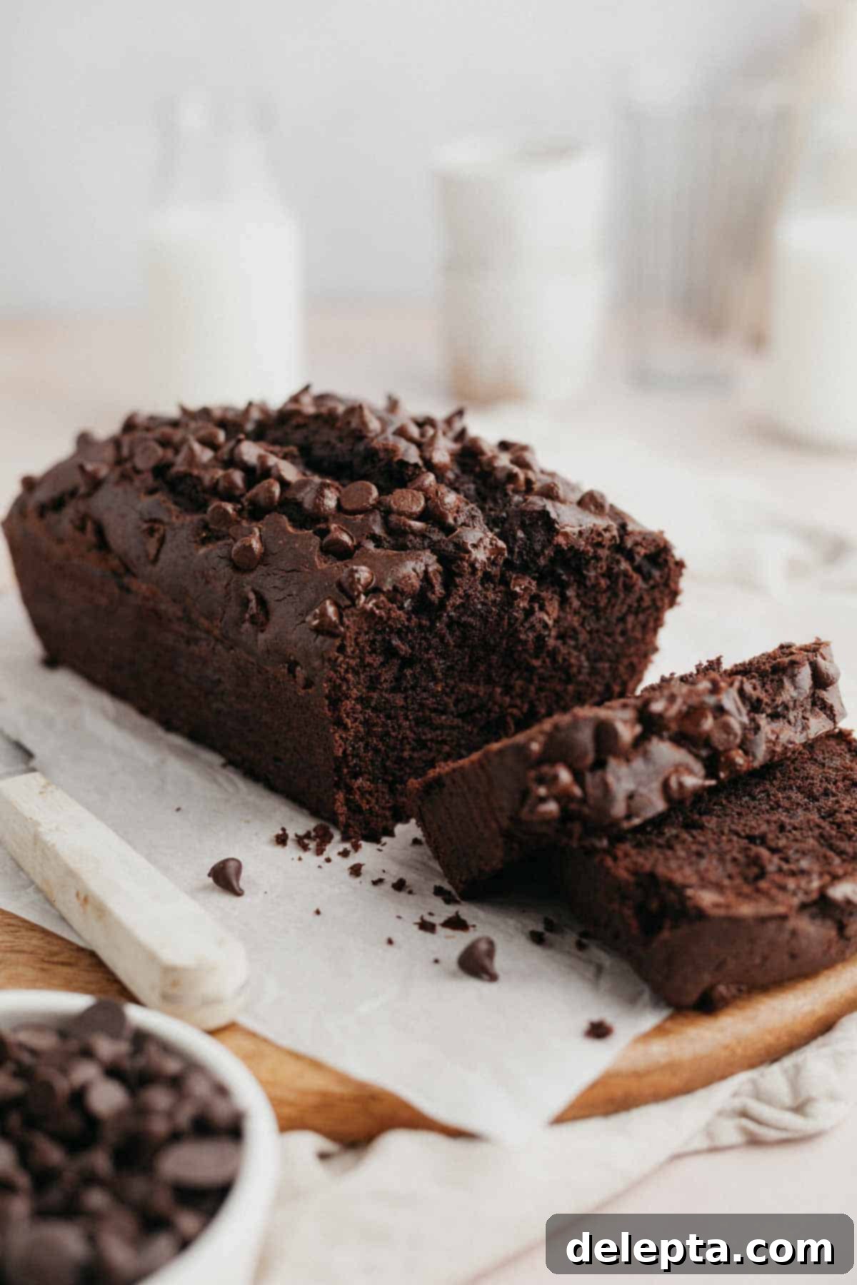 Velvety Chocolate Sour Cream Pound Cake 2 A beautifully sliced double chocolate sour cream pound cake on parchment paper, revealing its moist interior and chocolate chips. Two slices are neatly cut, ready to be enjoyed.