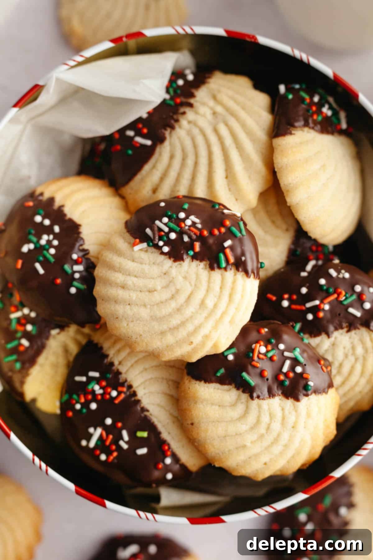 Decadent Chocolate Dipped Danish Butter Cookies 10 Beautifully decorated chocolate dipped butter cookies with festive sprinkles arranged neatly in a decorative tin.