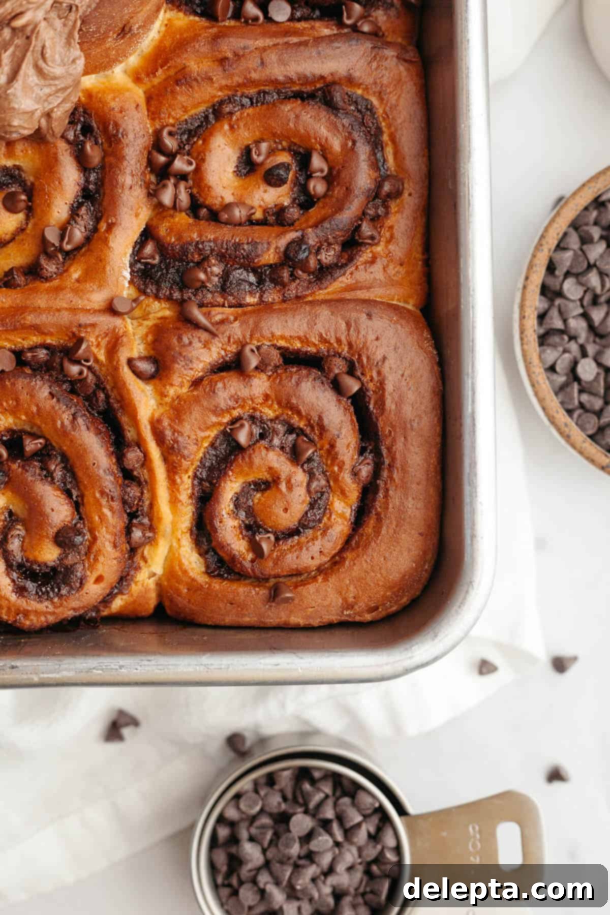 Decadent Double Chocolate Cinnamon Swirls 12 A close-up shot of several warm, gooey chocolate cinnamon rolls nestled in a white baking dish, fresh from the oven and awaiting frosting.