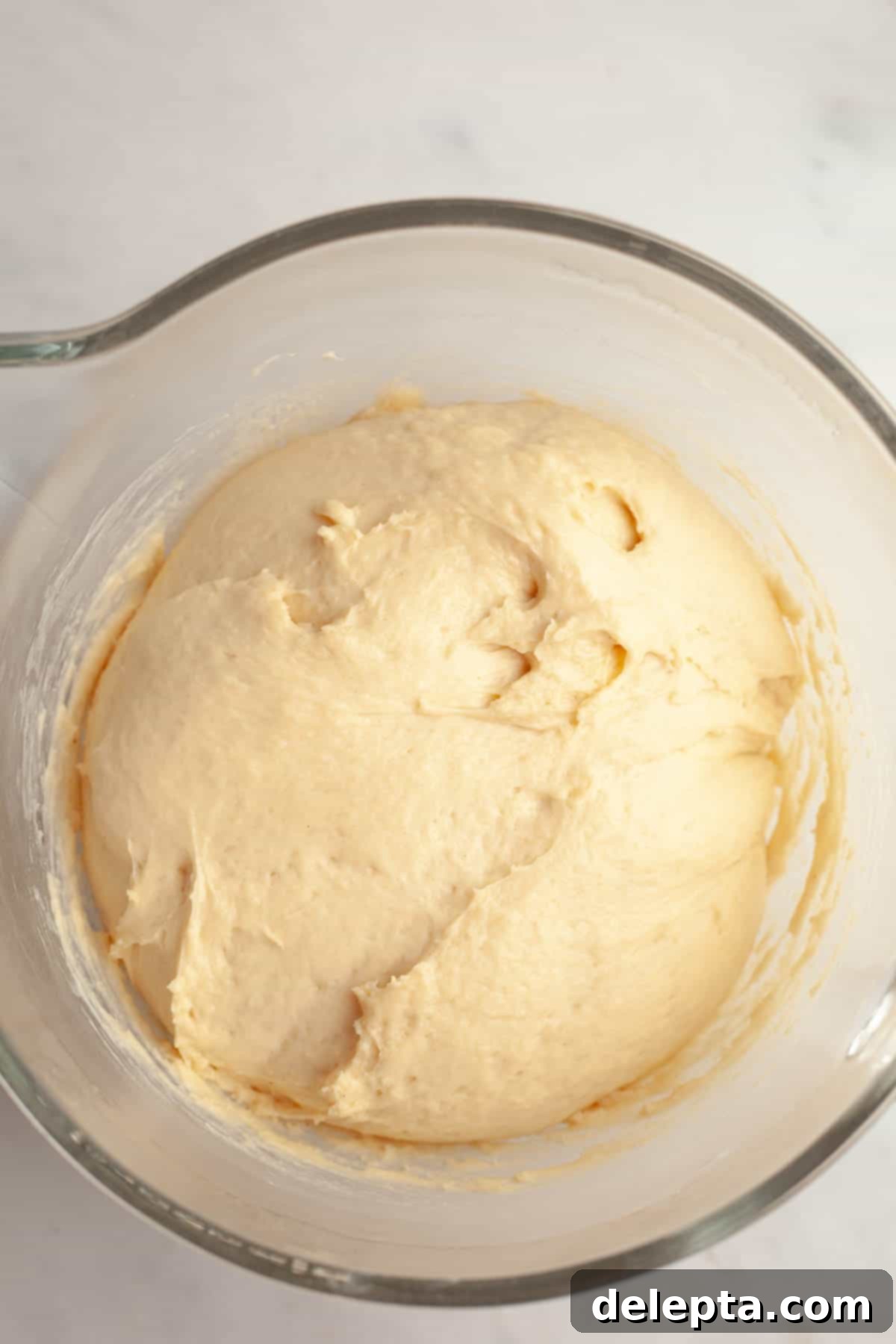 Decadent Double Chocolate Cinnamon Swirls 4 A fluffy brioche bread dough rests inside a clear glass mixing bowl, having risen perfectly.