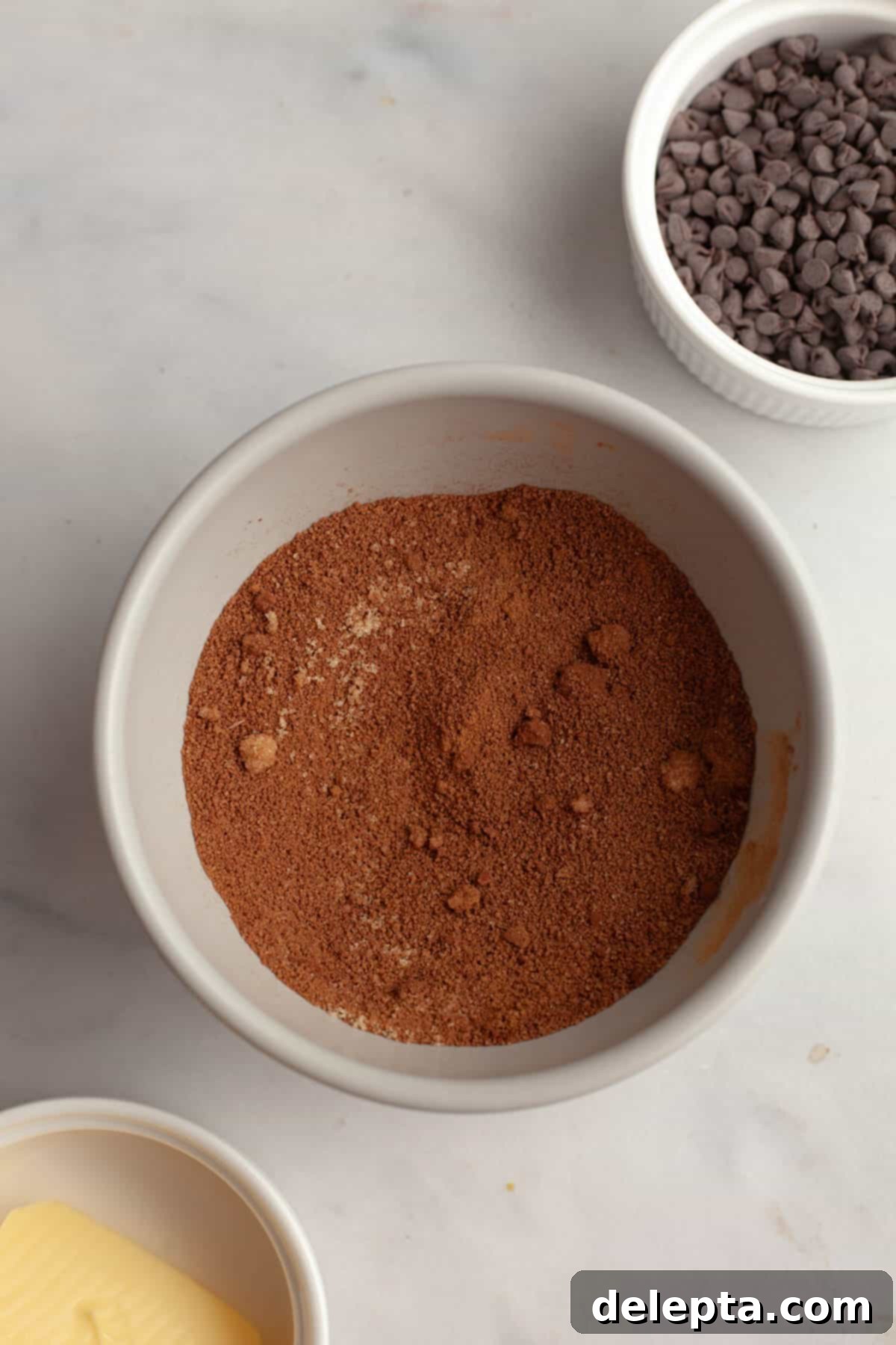 Decadent Double Chocolate Cinnamon Swirls 5 A small glass bowl containing a rich brown sugar, cinnamon, and cocoa powder mixture, ready for the cinnamon roll filling.