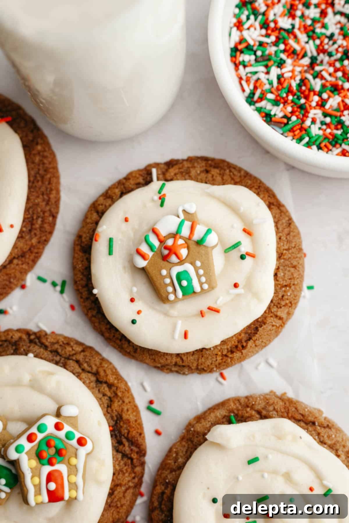 Velvet Gingerbread Cookies with Cream Cheese Frosting 13 A close-up of a stack of gingerbread cookies, each frosted with a generous layer of cream cheese and decorated with a tiny gingerbread house, creating a festive scene.